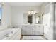 Bright bathroom featuring dual sinks, a bathtub, a large mirror, and light fixtures at 12187 S Hidden Trail Ct, Parker, CO 80138