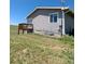 Side view of a tan house with a small wooden deck and overgrown yard at 15300 Cavanaugh Rd, Keenesburg, CO 80643