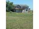 Charming two-story home with a large deck and attached garage is surrounded by an open, grassy lawn at 15300 Cavanaugh Rd, Keenesburg, CO 80643