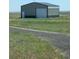 Large metal outbuilding with a roll-up door and pedestrian door, perfect for storage or workshop space at 15300 Cavanaugh Rd, Keenesburg, CO 80643