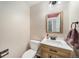 Cozy powder room featuring a wood-look vanity, white countertop, and a framed mirror with modern lighting at 10289 Dresden St, Firestone, CO 80504