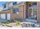 Close-up of the front entrance with brick facade, security door, and landscaped garden at 16261 W Ellsworth Ave, Golden, CO 80401