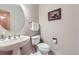 Neat powder room features pedestal sink, a round mirror and updated fixtures at 16261 W Ellsworth Ave, Golden, CO 80401