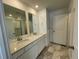 Bathroom featuring double sinks, granite countertop, mirrors, and tiled shower with glass door at 16562 E 109Th Ave, Commerce City, CO 80022
