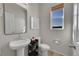 Well-lit half bathroom with a pedestal sink, modern fixtures, and a window with blinds at 5738 N Vivian St, Arvada, CO 80002
