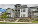 Three-story townhome featuring a red front door, stone accents, and dual upper level balconies at 16546 Umatilla Place, Broomfield, CO 80023