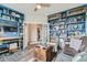 Spacious living room with custom blue built-in bookshelves, hardwood floors, and a dark leather couch at 16546 Umatilla Place, Broomfield, CO 80023
