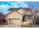 Charming two-story home featuring a tan and brown exterior, a front porch, an attached garage, and solar panels on the roof at 5563 S Elk Ct, Aurora, CO 80016