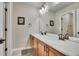 Bathroom featuring a double sink vanity with wood cabinets, a large mirror, neutral wall color, and tiled flooring at 2314 Fairway Wood Cir, Castle Rock, CO 80109