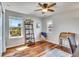 Bright bedroom featuring hardwood floors, ceiling fan, ladder shelf, and a cozy sitting area with scenic views from two windows at 2314 Fairway Wood Cir, Castle Rock, CO 80109