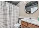 Bathroom featuring striped shower curtain, toilet and single sink vanity with a geometric shaped mirror at 12282 Bannock Cir # A, Denver, CO 80234