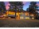 Back exterior of the residence with large windows and deck surrounded by tall trees and a sprawling lawn at 121 County Road 146, Elizabeth, CO 80107