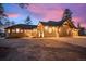 Stunning exterior view of a stone and wood home with a spacious driveway and a colorful sky at dusk at 121 County Road 146, Elizabeth, CO 80107