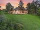 Expansive home featuring large windows, balconies, and a well-manicured lawn, all set against a picturesque sunset at 121 County Road 146, Elizabeth, CO 80107