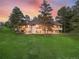 Expansive home featuring large windows, balconies, and a well-manicured lawn, all set against a picturesque sunset at 121 County Road 146, Elizabeth, CO 80107