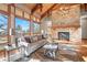 Bright living room featuring a stone fireplace, hardwood floors, and large windows offering scenic views at 121 County Road 146, Elizabeth, CO 80107