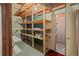Basement storage room with wood shelving and visible ceiling joists and a door to the main area at 6114 Miller St, Arvada, CO 80004