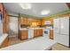 Well-lit kitchen featuring wood cabinets, white appliances, and a speckled countertop at 6114 Miller St, Arvada, CO 80004