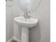 Close-up of a pedestal sink with a modern faucet and a round mirror in a minimalist bathroom setting at 19089 E 94Th Pl, Commerce City, CO 80022