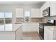 Modern kitchen featuring white cabinets, stainless steel appliances, a center island, and access to the backyard at 19089 E 94Th Pl, Commerce City, CO 80022