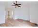Large bedroom with light hardwood flooring, ceiling fan and two open doorways to baths at 8197 S Fillmore Way, Centennial, CO 80122