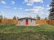 Backyard shed with red door, surrounded by green grass and bordered by a wooden fence, creating a private outdoor space at 9667 W Ohio Ave, Lakewood, CO 80226