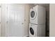 Bright laundry room featuring stacked washer and dryer, plus access to door and utility connections at 20801 Randolph Pl, Denver, CO 80249