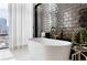 Bathroom with freestanding tub and dark tile, offering city views at 1901 Wazee St # 1401, Denver, CO 80202