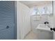 Quaint bathroom with blue accents, shower with curtain, window, and white vanity at 2717 S Steele St, Denver, CO 80210