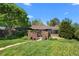 Charming brick home with a lush green lawn and mature trees on a sunny day at 2717 S Steele St, Denver, CO 80210