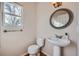 Cozy half bathroom featuring a pedestal sink, decorative mirror, and window at 3938 Lazy K Dr, Castle Rock, CO 80104