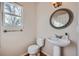 Powder room featuring pedestal sink, decorative mirror, wood-look floors, and natural light at 3938 Lazy K Dr, Castle Rock, CO 80104