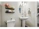 Charming half bathroom featuring a pedestal sink, decorative shelves, and modern fixtures with a clean design at 19221 E 65Th Ave, Denver, CO 80249