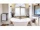 Bright bathroom with a soaking tub, frosted windows, dual vanities, and wood-look tile flooring at 6414 E Stanford Ave, Cherry Hills Village, CO 80111