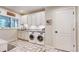 Functional laundry room with white cabinetry, granite counters, and modern washer and dryer units at 6414 E Stanford Ave, Cherry Hills Village, CO 80111