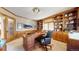 Bright home office featuring wooden built-in shelves, a large desk, and neutral carpet flooring at 6414 E Stanford Ave, Cherry Hills Village, CO 80111