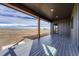 View of covered patio with gray stained wood floor boards overlooking beautiful landscape at 1740 Joseph Cir, Elizabeth, CO 80107