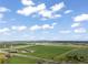 Sprawling aerial view showcasing open land, farm buildings, roads, and distant town against a cloudy sky at 1805 W County Road 8, Berthoud, CO 80513