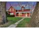 Charming two-story red home with a covered front porch, surrounded by mature trees and lush green lawn at 1805 W County Road 8, Berthoud, CO 80513