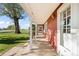 Covered porch with views of open lawn, a mature tree, and a red home facade at 1805 W County Road 8, Berthoud, CO 80513