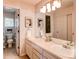 Well-lit bathroom featuring a double vanity, neutral color scheme, and decorative wall art at 5473 W Prentice Ct, Littleton, CO 80123