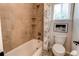Bathroom features tiled shower with shelves, a bathtub, and a toilet near the window at 5473 W Prentice Ct, Littleton, CO 80123