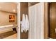 The tan bathroom features a stall shower with a white decorative curtain at 5473 W Prentice Ct, Littleton, CO 80123