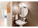 Stylish powder room with a round mirror and pedestal sink, adjacent to the staircase at 5473 W Prentice Ct, Littleton, CO 80123