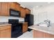 Bright kitchen with wood cabinets, black appliances, and tile floors at 19060 E 54Th Pl, Denver, CO 80249