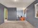 Open bedroom leading to bathroom in remodel state; gray walls and carpet at 7737 S Dover St, Littleton, CO 80128