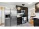 Updated kitchen features stainless steel appliances, dark cabinetry, and a view into the dining room at 1060 S Harrison St, Denver, CO 80209
