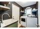 Efficient laundry room with floating shelves, a utility sink, and modern washer and dryer units at 1932 Sandhurst Dr, Castle Rock, CO 80104