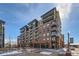 Modern condo building featuring brick facade, glass balconies, and sleek architectural design against a clear blue sky at 20 Wilcox St # 518, Castle Rock, CO 80104