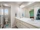 Bright bathroom featuring double sinks, a large mirror, white cabinets and tiled floor and an adjacent toilet room at 15194 W Washburn Ave, Lakewood, CO 80228